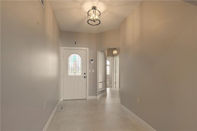 entryway with an inviting chandelier, lofted ceiling, and light tile patterned flooring