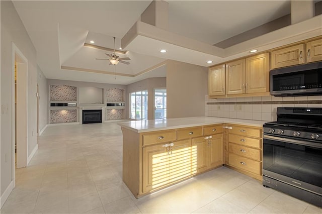 kitchen with kitchen peninsula, appliances with stainless steel finishes, a tray ceiling, and light brown cabinetry