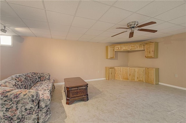 living area with a paneled ceiling and ceiling fan