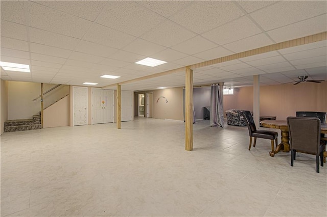 basement with a paneled ceiling and ceiling fan