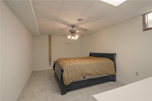 bedroom featuring ceiling fan, a drop ceiling, and light tile patterned floors