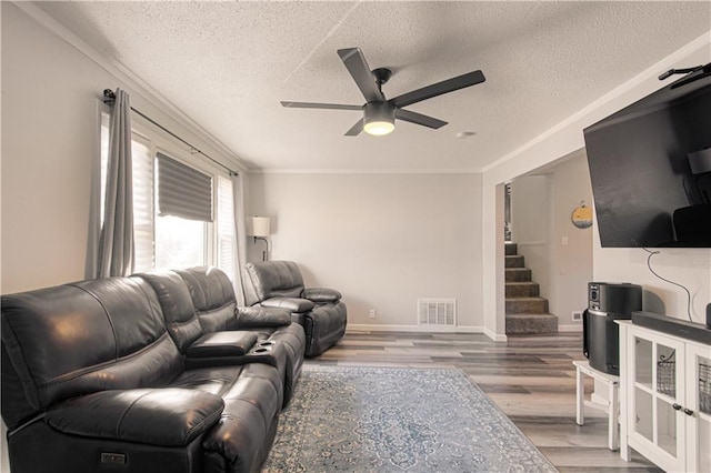 living room featuring ceiling fan, crown molding, wood-type flooring, and a textured ceiling