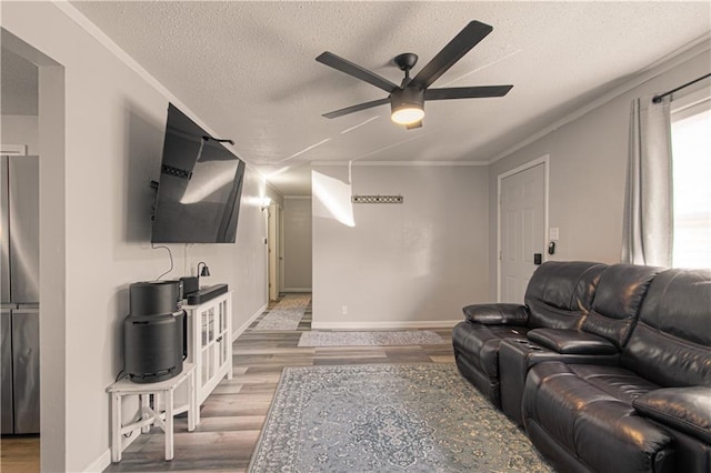 living room with ceiling fan, light hardwood / wood-style floors, crown molding, and a textured ceiling