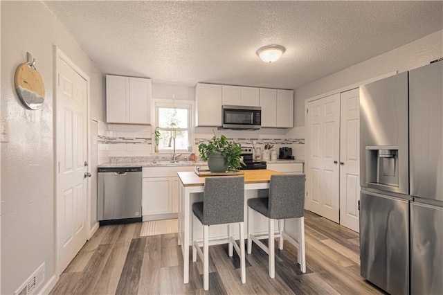 kitchen with white cabinets, stainless steel appliances, a kitchen island, and sink