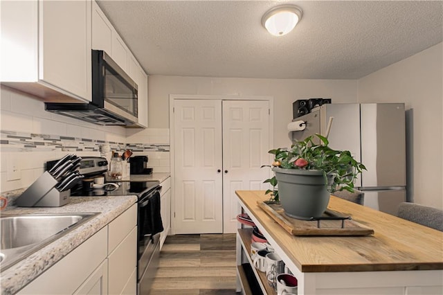 kitchen with white cabinets, butcher block countertops, a textured ceiling, and appliances with stainless steel finishes