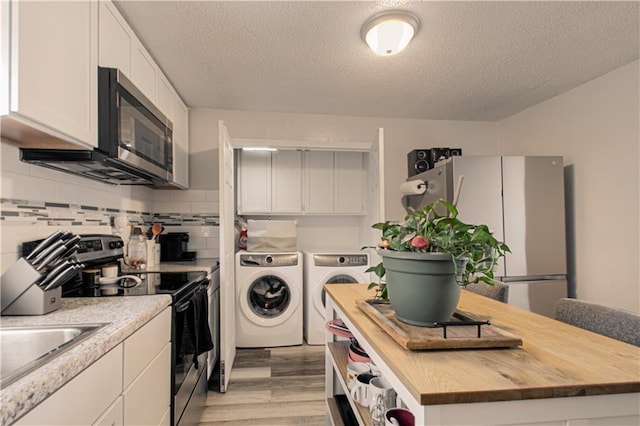 kitchen with washer and clothes dryer, white cabinets, a textured ceiling, and appliances with stainless steel finishes