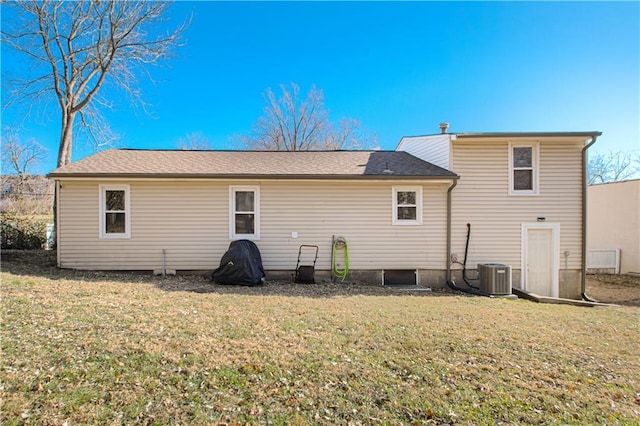 rear view of property featuring a lawn and central AC unit