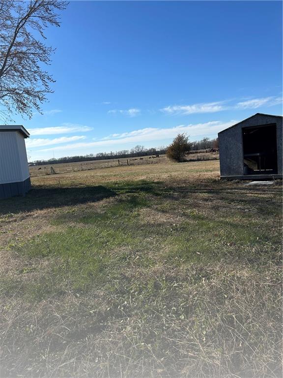 view of yard featuring a rural view and a storage shed