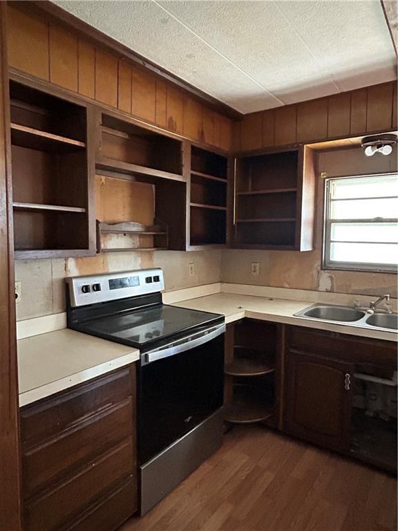 kitchen featuring stainless steel electric range oven, sink, wall chimney range hood, dark hardwood / wood-style flooring, and a textured ceiling