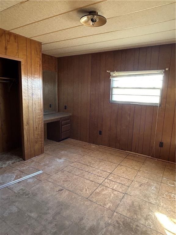 unfurnished bedroom featuring wooden walls and a closet