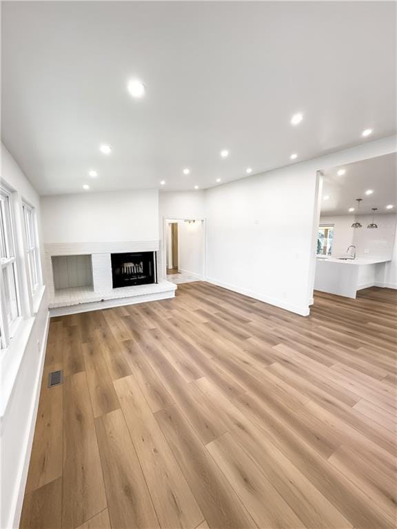 unfurnished living room with light wood-type flooring and sink