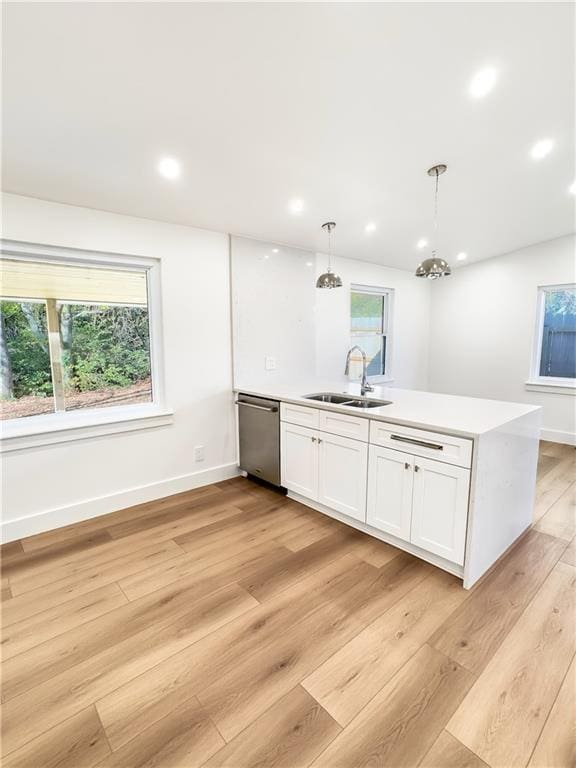 kitchen with dishwasher, white cabinets, sink, hanging light fixtures, and light hardwood / wood-style floors