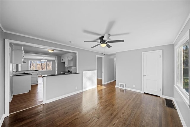 unfurnished living room with a wealth of natural light, ceiling fan, and dark wood-type flooring