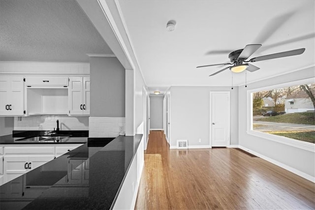 kitchen with white cabinetry, sink, tasteful backsplash, crown molding, and hardwood / wood-style floors