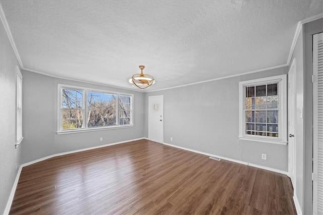 empty room with dark hardwood / wood-style floors, crown molding, and a textured ceiling