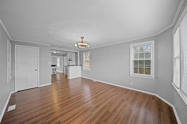 unfurnished living room featuring a healthy amount of sunlight, dark hardwood / wood-style flooring, and crown molding