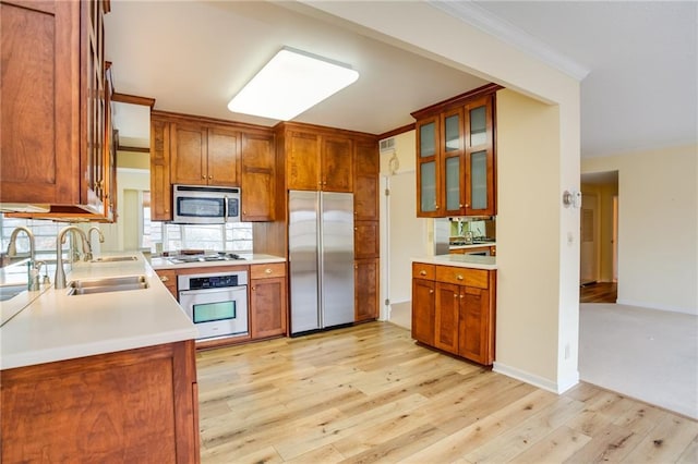 kitchen with ornamental molding, sink, light hardwood / wood-style floors, and appliances with stainless steel finishes