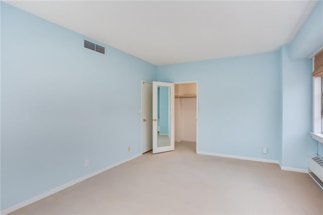 unfurnished bedroom featuring a walk in closet, a closet, and light colored carpet