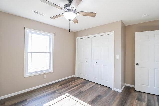 unfurnished bedroom featuring ceiling fan, a closet, dark hardwood / wood-style floors, and multiple windows