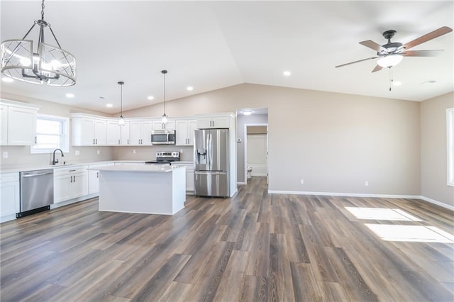 kitchen with dark wood-type flooring, a kitchen island, pendant lighting, and appliances with stainless steel finishes