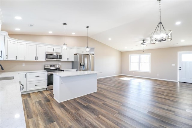 kitchen with appliances with stainless steel finishes, dark hardwood / wood-style flooring, ceiling fan, pendant lighting, and white cabinetry