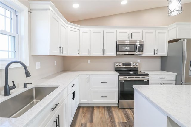 kitchen featuring sink, white cabinets, vaulted ceiling, and appliances with stainless steel finishes