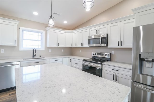 kitchen featuring lofted ceiling, white cabinets, hanging light fixtures, sink, and appliances with stainless steel finishes