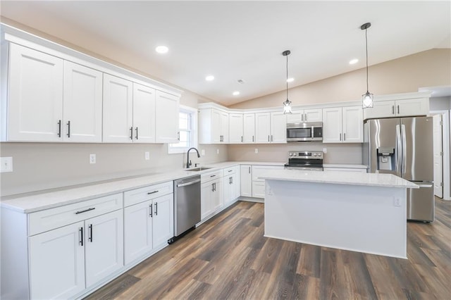 kitchen with decorative light fixtures, a kitchen island, lofted ceiling, and appliances with stainless steel finishes