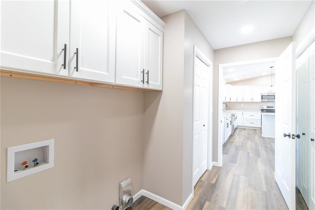 clothes washing area featuring light hardwood / wood-style floors, cabinets, sink, and hookup for a washing machine