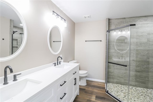 bathroom with a shower with door, vanity, wood-type flooring, and toilet