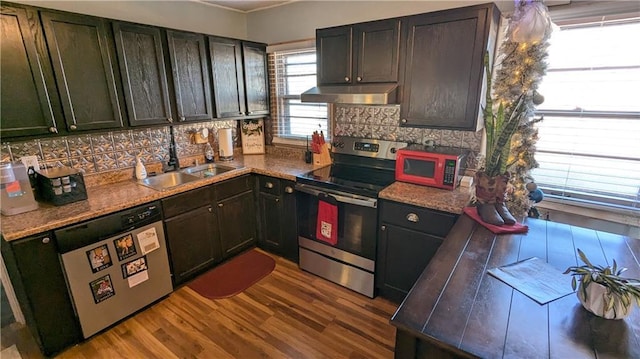 kitchen with sink, stainless steel appliances, stone countertops, and hardwood / wood-style flooring