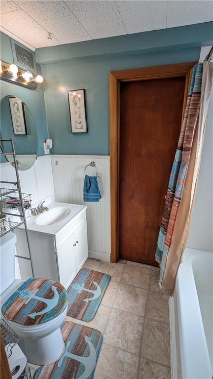 full bathroom featuring shower / bath combo, vanity, toilet, and a paneled ceiling