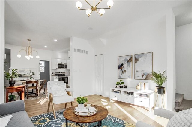 living room with light hardwood / wood-style floors and an inviting chandelier