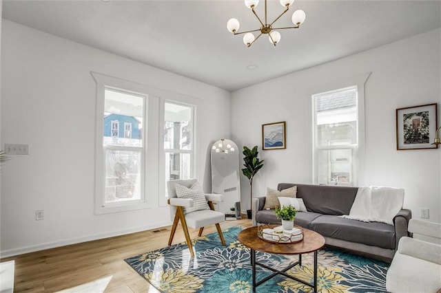 living room with a healthy amount of sunlight, a notable chandelier, and wood-type flooring