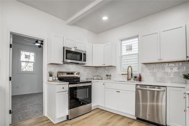 kitchen with white cabinetry, sink, tasteful backsplash, light hardwood / wood-style floors, and appliances with stainless steel finishes