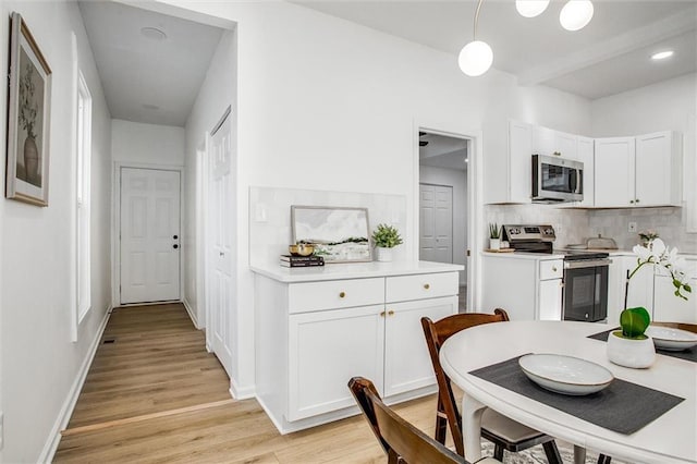 kitchen featuring white cabinets, decorative backsplash, stainless steel appliances, and light hardwood / wood-style floors