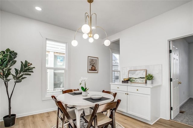 dining area with an inviting chandelier and light hardwood / wood-style flooring