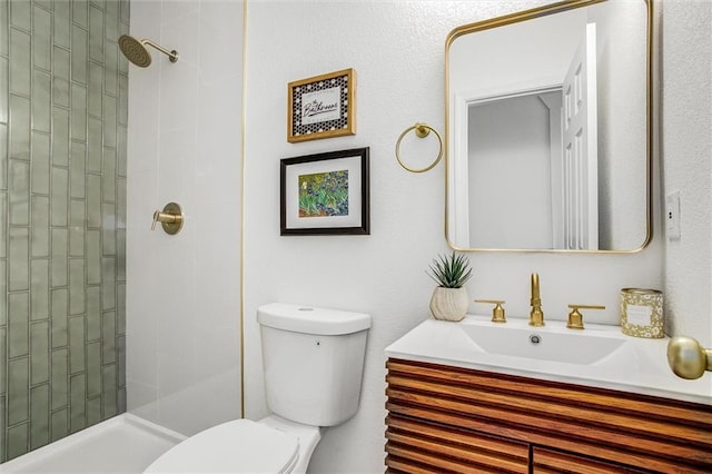 bathroom featuring a tile shower, vanity, and toilet