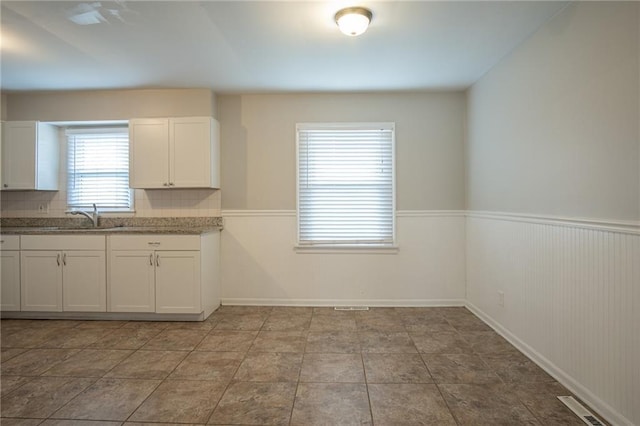 kitchen with white cabinets, light tile patterned floors, tasteful backsplash, and sink