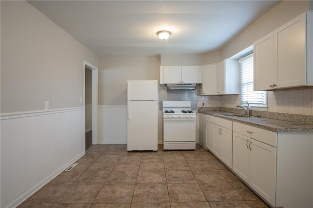 kitchen with light stone countertops, tasteful backsplash, white appliances, sink, and white cabinets