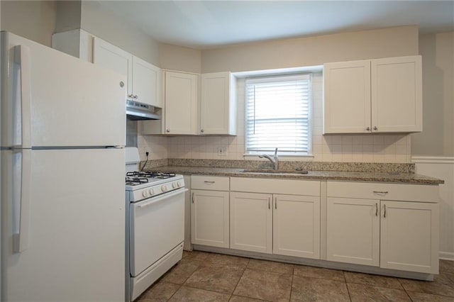 kitchen with white appliances, backsplash, white cabinets, sink, and stone countertops