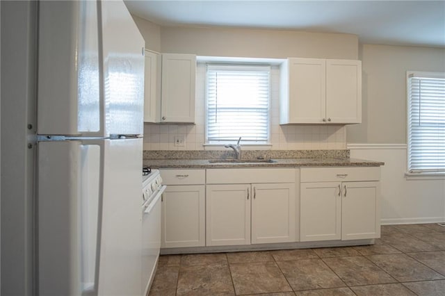 kitchen with backsplash, white cabinets, white appliances, and sink