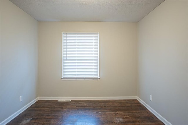 spare room with a textured ceiling and dark wood-type flooring