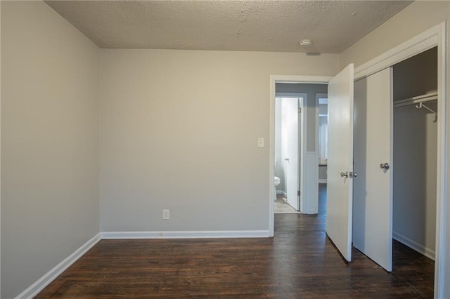 unfurnished bedroom featuring a textured ceiling, a closet, and dark hardwood / wood-style floors