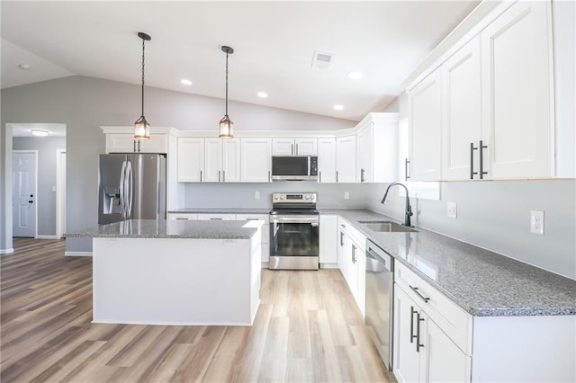 kitchen with sink, a center island, lofted ceiling, white cabinets, and appliances with stainless steel finishes