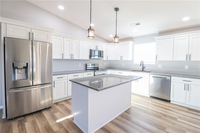 kitchen with white cabinets, sink, vaulted ceiling, light wood-type flooring, and stainless steel appliances