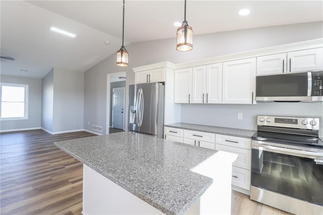 kitchen featuring white cabinetry, hardwood / wood-style floors, decorative light fixtures, vaulted ceiling, and appliances with stainless steel finishes