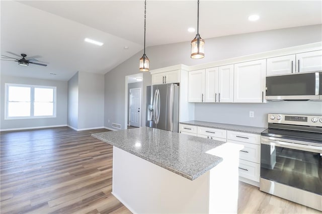 kitchen with pendant lighting, vaulted ceiling, light wood-type flooring, white cabinetry, and stainless steel appliances