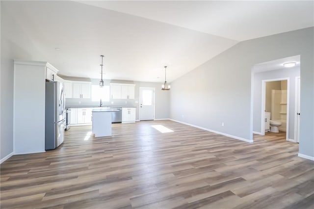 unfurnished living room with light wood-type flooring, lofted ceiling, and sink