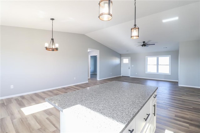 unfurnished living room featuring hardwood / wood-style floors, ceiling fan with notable chandelier, and vaulted ceiling